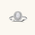 Sterling silver ring with oval moissanite center stone surrounded by double halo of sparkling stones on neutral background.