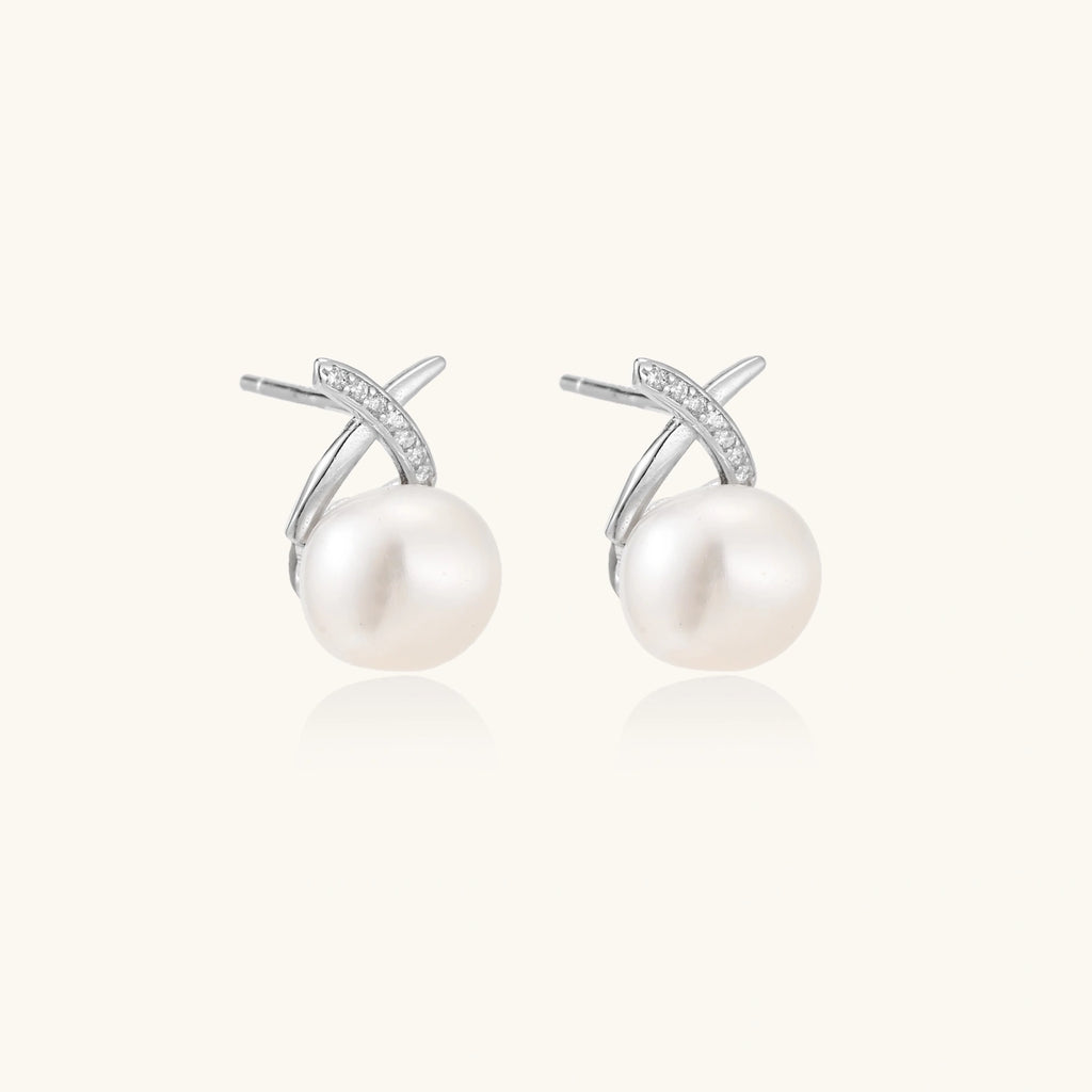 Rhodium-plated silver stud earrings with sparkling X design above lustrous round freshwater pearls on white background.
