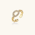 Gold-plated brass chain link ring with one oval CZ-pavé segment on cream background, adjustable cuff style.