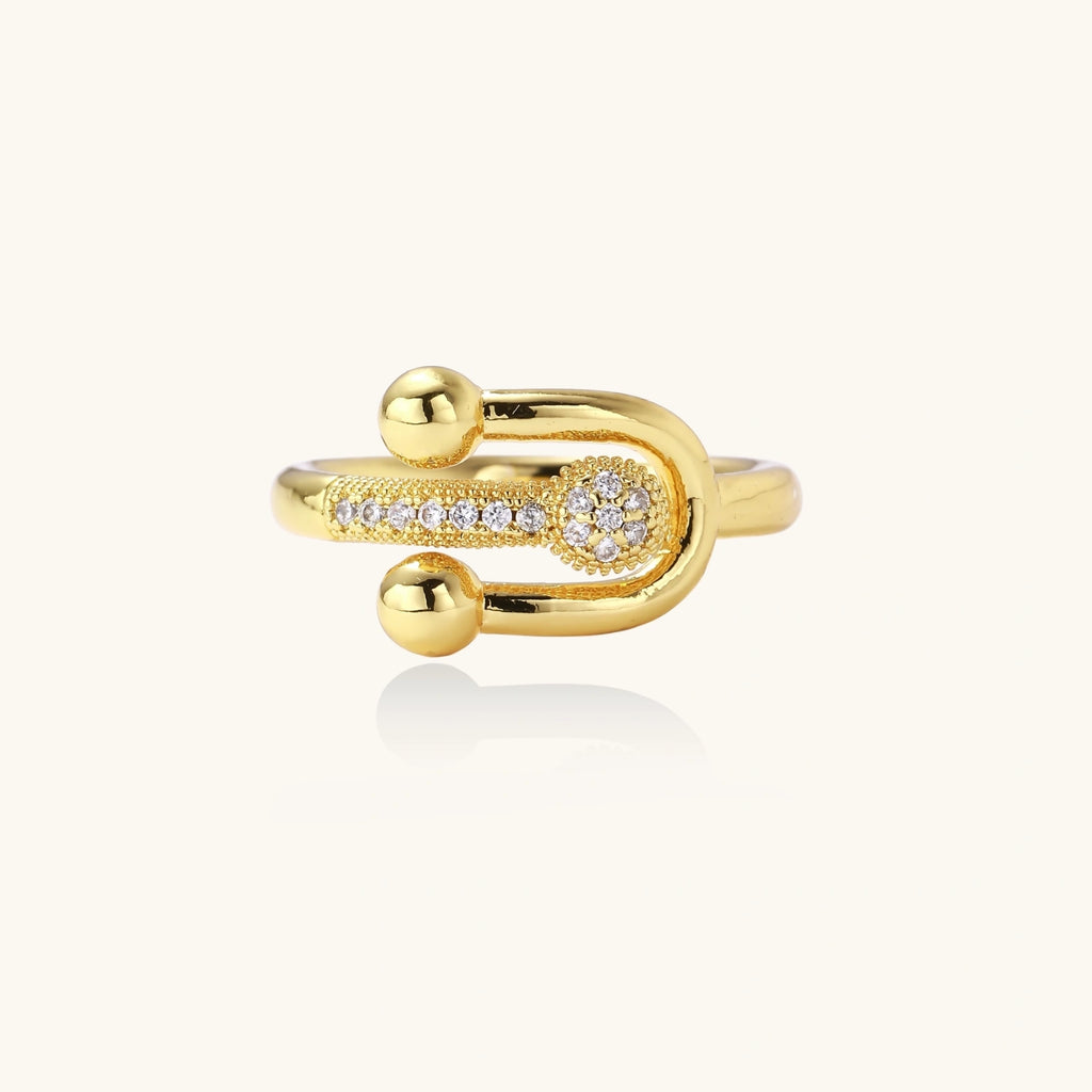 Gold-plated brass ring with safety pin design featuring pavé cubic zirconia stones and dual sphere ends