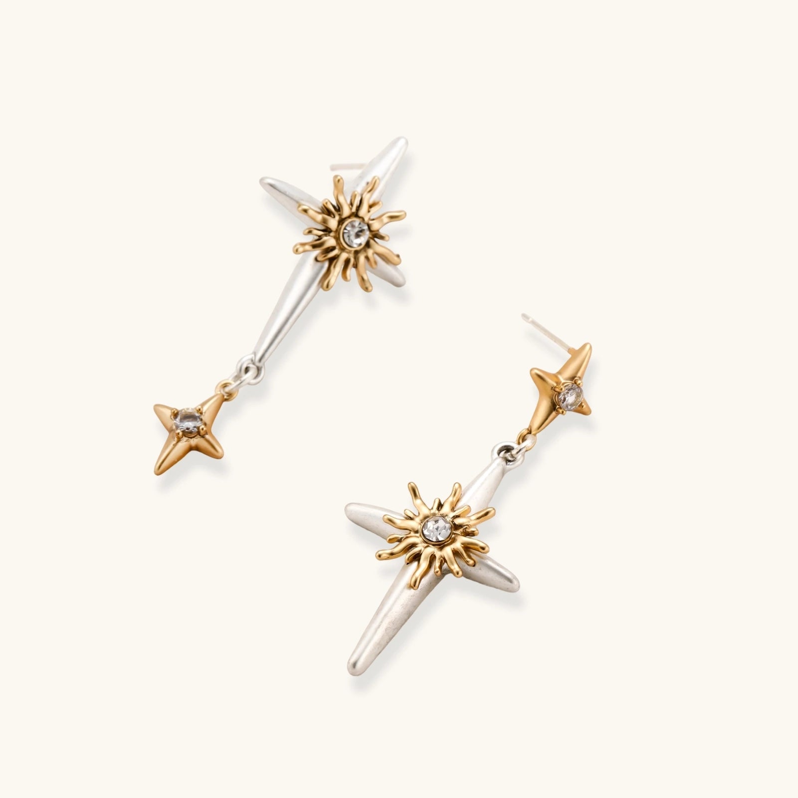 Layered silver-toned necklace set with cross pendant and gold sun charm detail, matching drop earrings on white background.