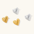 Pair of textured heart-shaped stud earrings in brushed platinum-plated sterling silver against cream background.