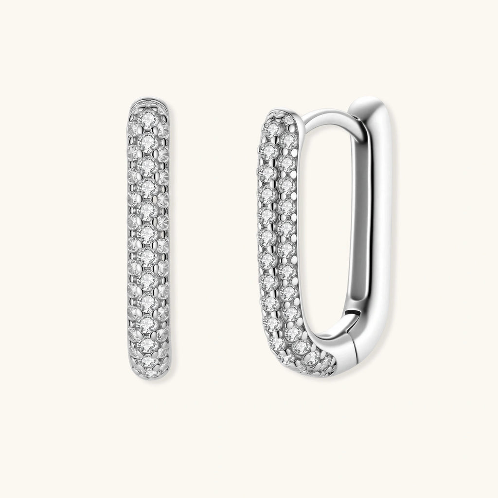 Close-up of platinum-plated sterling silver huggie hoops with pavé crystal setting on white background.