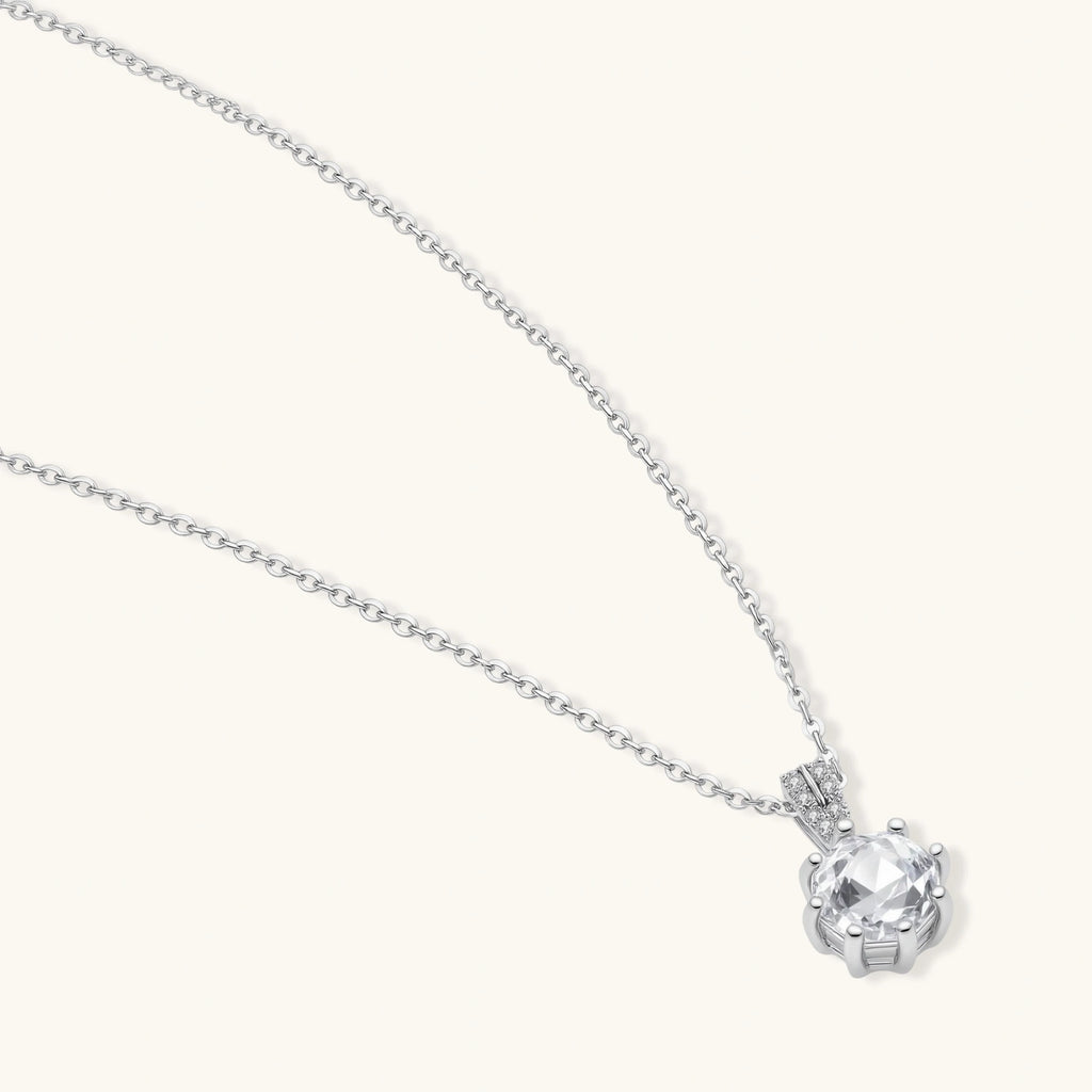 Platinum-plated sterling silver necklace with round clear crystal pendant and decorative bail on neutral background.