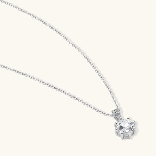 Platinum-plated sterling silver necklace with round clear crystal pendant and decorative bail on neutral background.