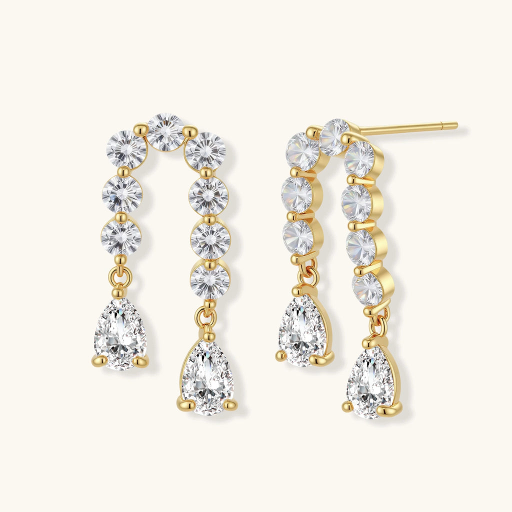 Gold-plated earrings with vertical line of clear crystals and teardrop pendants on neutral background