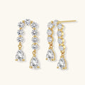 Gold-plated earrings with vertical line of clear crystals and teardrop pendants on neutral background