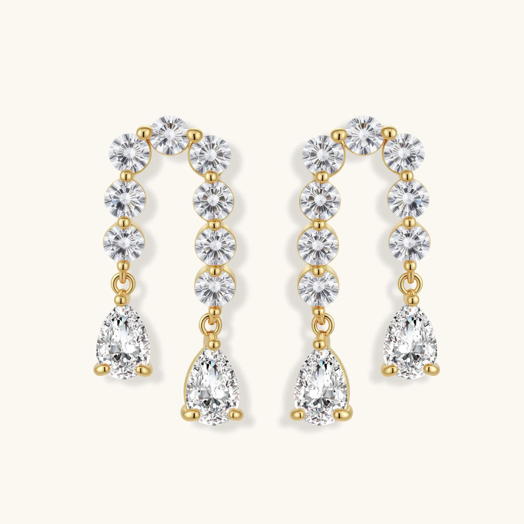 Gold-plated earrings with vertical line of clear crystals and teardrop pendants on neutral background