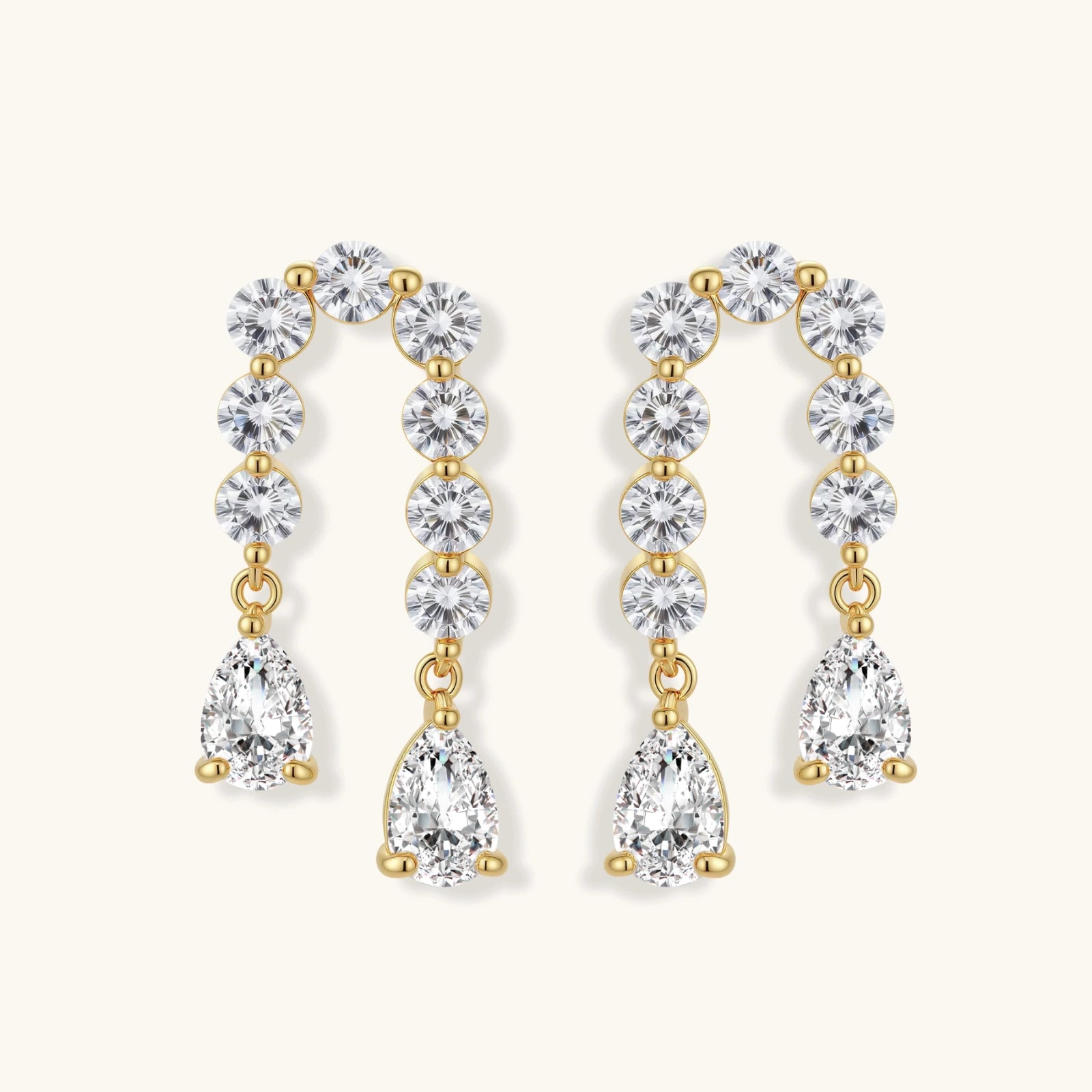 Gold-plated earrings with vertical line of clear crystals and teardrop pendants on neutral background