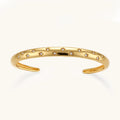 Polished 18K gold plated cuff bracelet with cubic zirconia set in star motifs on a cream background.